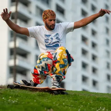 Longboarder in funky pants riding in the grass