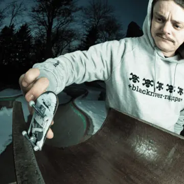 Pro fingerboard skater esegue trick sulla rampa