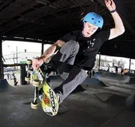 Skateboarder jumping out of the ramp wearing a skate helmet